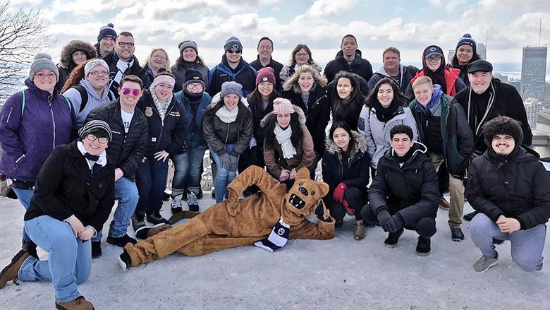 Group of Penn State students and chaperones pose in a lofty patio area overlooking Montreal